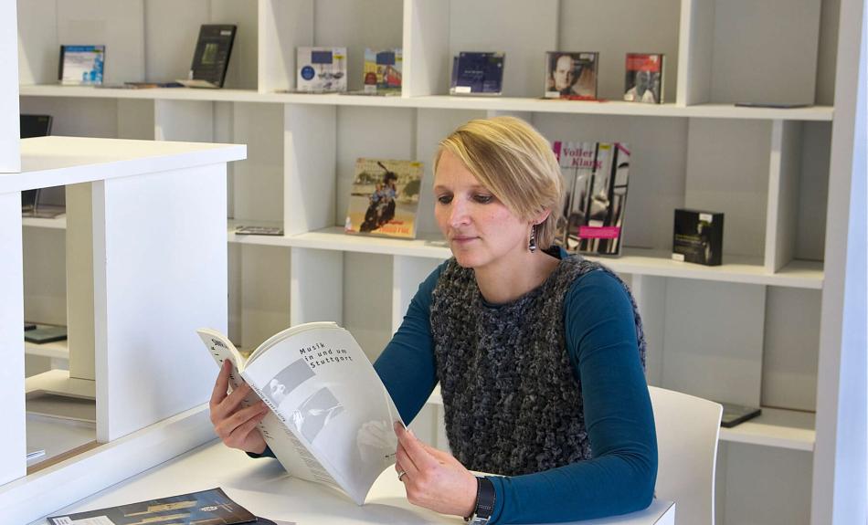 Eine Frau liest an einem Tisch in einer Bibliothek Zeitschriften