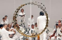 Während der Aufführung von "Las Passione" ist das Orchester ganz in weiß gekleidet. Im Vordergrund ist ein großer goldener Ring aus Draht positioniert, der an eine Dornenkrone erinnert.