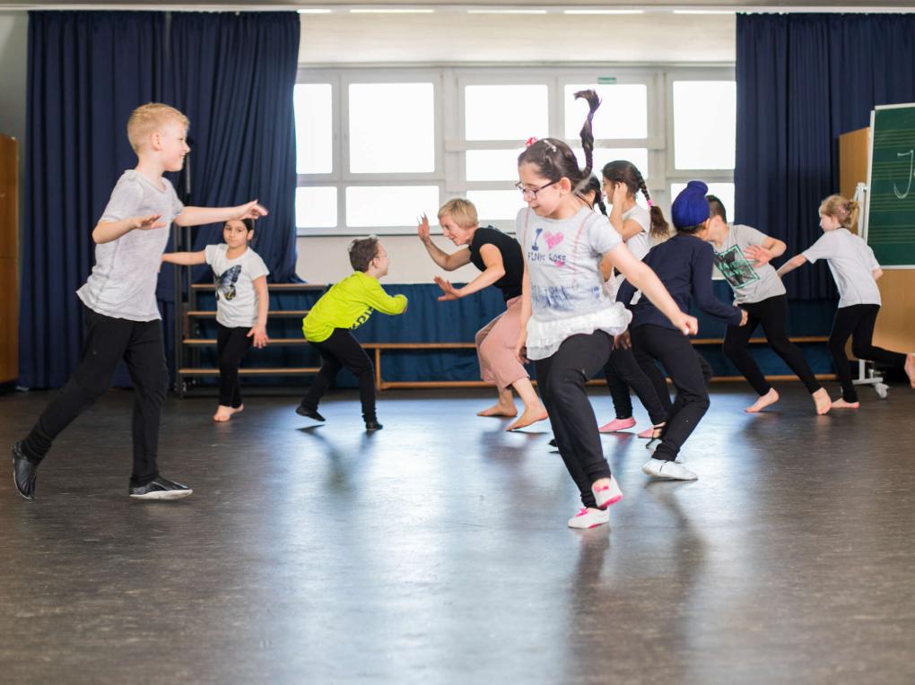 Eine Gruppe Kinder tanzt durch einen Raum