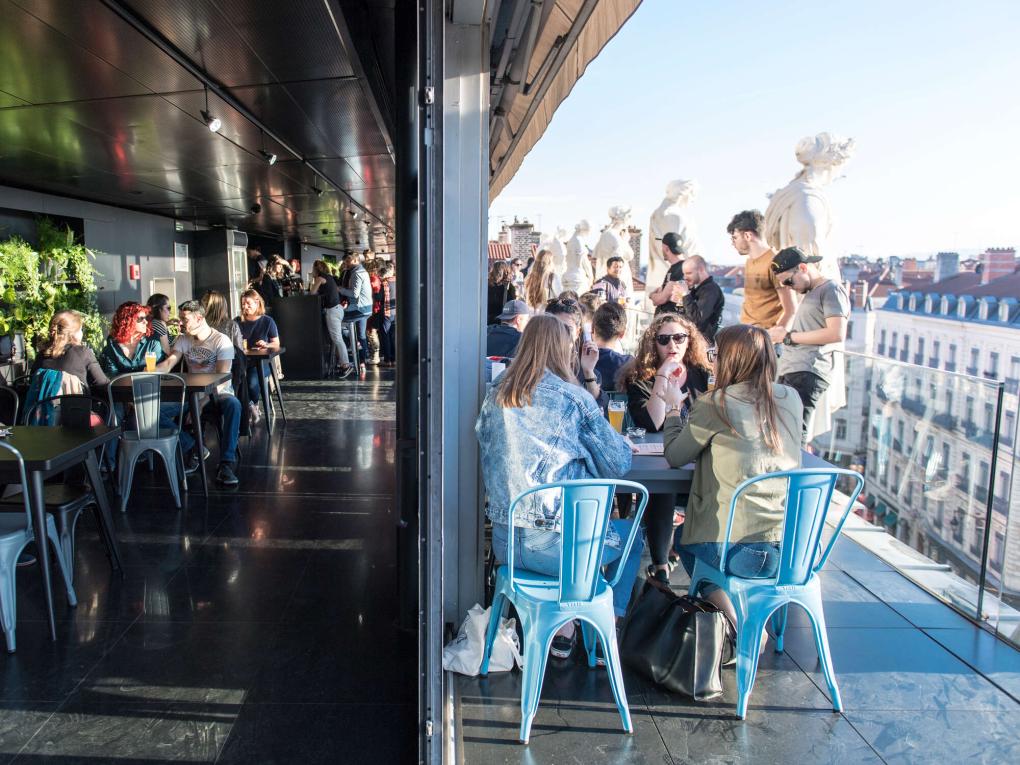 Menschengruppen an Restauranttischen auf einer Dachterrasse